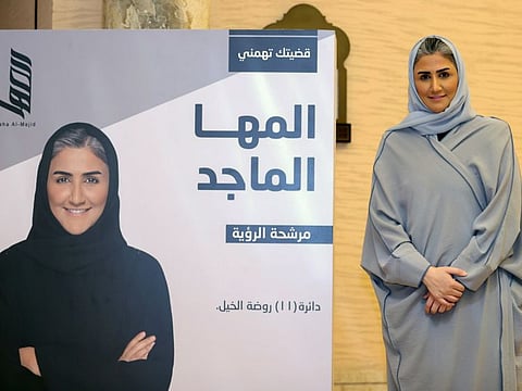 Al Maha Al Majid, a candidate in Qatar's Shura Council election, poses for a photo next to an election poster in Doha in a file photo.