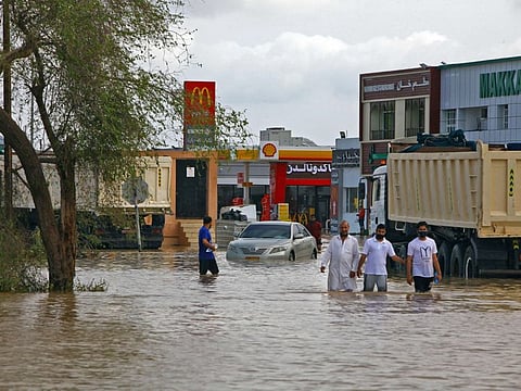 People wade through a flooded street in the aftermath of tropical Cyclone Shaheen in Oman's northern town of Al Mussanah on October 4, 2021. 