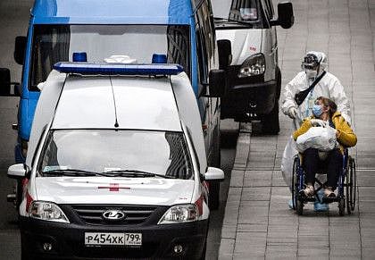 A medic staff member pushes a woman on a wheelchair at a hospital for the COVID-19 infected patients at Kommunarka outside Moscow on October 5, 2021. 