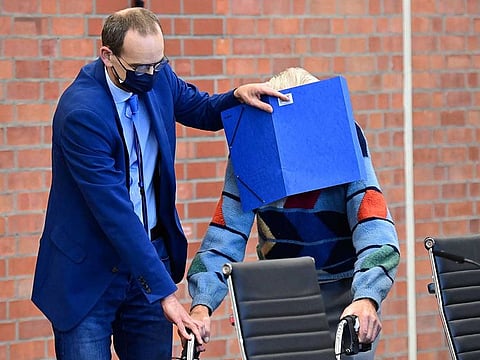 Defendant Josef S gets help from his lawyer Stefan Waterkamp (L) to hide his face behind a folder as he arrives for his trial in Brandenburg an der Havel, northeastern Germany, on October 7, 2021. 