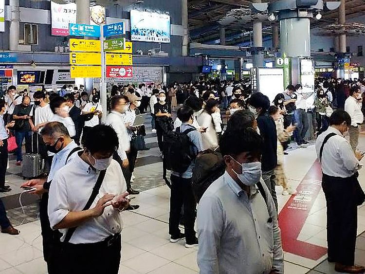 Passengers are seen outside the entrance of JR Shinagawa station as the railway company makes safety check following an earthquake, in Tokyo, on Thursday, October 7, 2021.