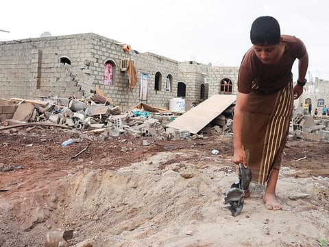 A boy holds shrapnel of a missile at the site of an Al Houthi missile attack in Marib, on October 3, 2021. 