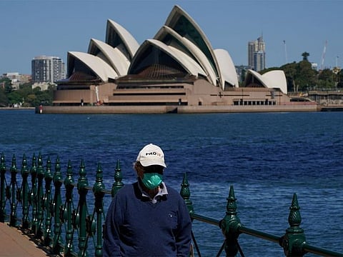 A person in protective face mask walks along the harbour waterfront across from the Sydney Opera House during a lockdown to curb the spread of COVID-19 outbreak in Sydney, Australia on October 6, 2021.