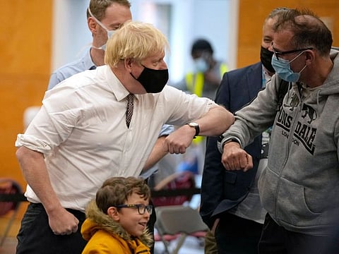 British Prime Minister Boris Johnson (left) greets members of the public at a vaccination centre at Little Venice Sports Centre in London on October 22, 2021.  