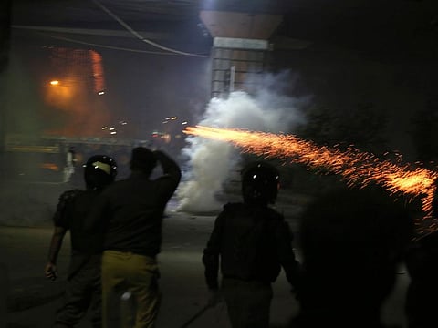 Police officers fire tear gas shell to disperse the supporters of Tehreek-e-Labiak Pakistan  in Lahore.