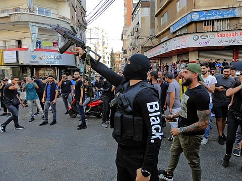 A member of Lebanon's Hezbollah movement fires his gun during the the funeral of some of their members who were killed during clashes in the Tayouneh neighbourhood of the capital Beirut's southern suburbs a day earlier, on October 15, 2021. 