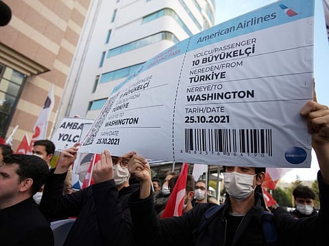 Members of a Turkish group hold a symbolic boarding pass for 10 foreign ambassadors as they stage a protest near the US Embassy to support Turkey's President Recep Tayyip Erdogan, in Ankara, on October 25, 2021. 