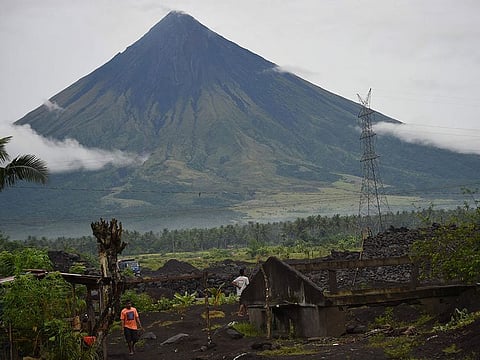 State volcanologists urged the public to exercise caution and avoid going inside the Permanent Danger Zone's 6-km radius. File photo shows residents walking past a house half-buried by sand and rock from Mayon volcano.