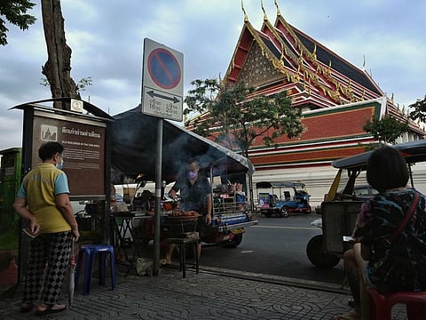 A vendor cooking sausages from the back of an unused tuk tuk vehicle behind Wat Pho Buddhist temple, a popular tourist spot near the Grand Palace, in Bangkok on Oceber 25, 2021..  