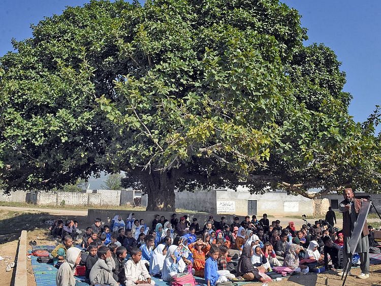 Students of the community school in Sector E-13 of Islamabad taking their lessons under a tree.  
