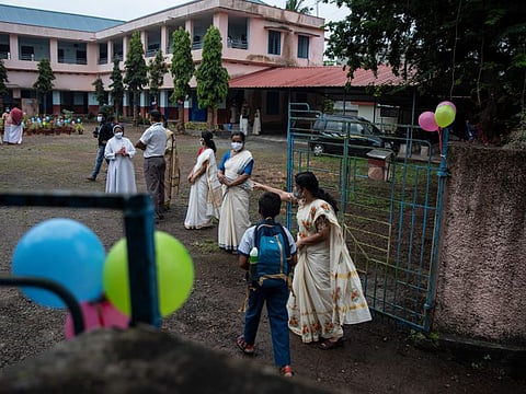 A teacher guides a student to his classroom as schools reopened in Kochi, Kerala on November 1, 2021.  