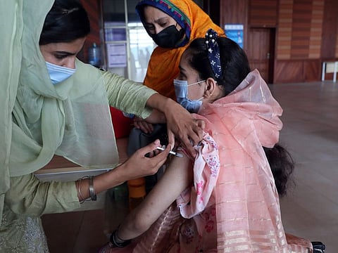 A woman receives the Pfizer COVID-19 vaccine from a health worker in Islamabad in a file photo.