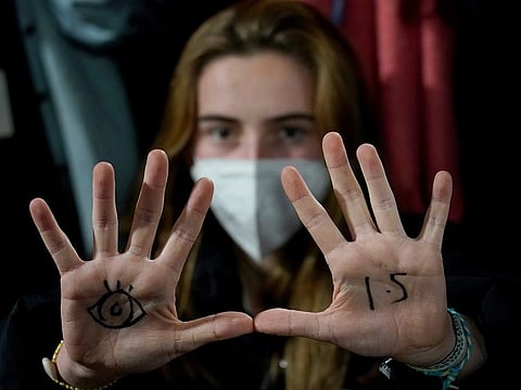 A woman, with an eye drawn on her hand to show she is watching and 1.5 for countries to limit warming to 1.5 degrees Celsius, takes part in a protest inside a plenary corridor at the SEC (Scottish Event Campus) venue for the COP26 UN Climate Summit, in Glasgow, Scotland, on November 10, 2021. 