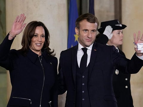 French President Emmanuel Macron and Vice President Kamala Harris wave November 10, 2021 at the Elysee Palace in Paris. France is hosting an international conference on Libya on Friday as the North African country heads into long-awaited elections next month, a vote that regional and world powers hope will pull the oil-rich nation out of its decade-old chaos. 