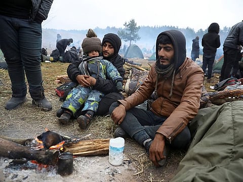 Migrants sit around a bonfire in a camp near Bruzgi-Kuznica checkpoint on the Belarusian-Polish border 