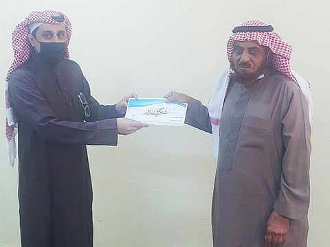 Saleh Mefrah receives a certificate of appreciation for his perseverance from a local school manager. 