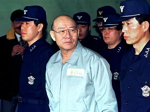 Former South Korean president Chun Doo-hwan, wearing a prison uniform, is escorted by police into the Seoul District Criminal Court where he is on trial facing corruption charges in this file photo taken in 1996.