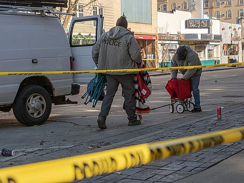 Police collect abandoned items along a parade route in Waukesha, Wis., on Monday, Nov. 22, 2021, after the driver of an SUV plowed into a Christmas parade on Sunday.
