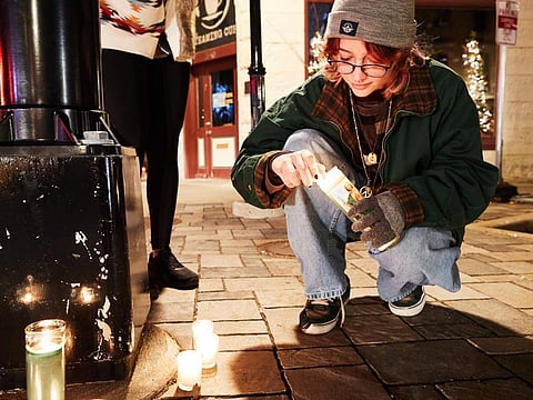 People light candles at a makeshift memorial along the route of the parade on W Main Street in Waukesha, Wisconsin on November 22, 2021.