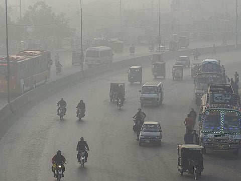 Commuters make their way along a road amid smoggy conditions in Lahore. 