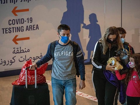 Travellers wearing protective face masks arrive to Ben Gurion Airport near Tel Aviv on November 28, 2021. 