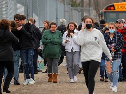 Parents walk away with their kids from the Meijer’s parking lot in Oxford where many students gathered following an active shooter situation at Oxford High School, Tuesday, Nov. 30, 2021, in Oxford, Mich. 