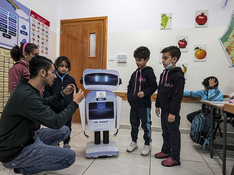 Palestinian teacher Hassan Al Razi gives a science class to students in his classroom while aided by a locally-made educational robot, at a private school in Gaza City on November 30, 2021. 