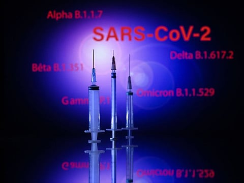 This photograph taken on December 2, 2021, shows a syringe and a screen displaying the SARS-Cov-2 mains variants : Alpha, Beta, Delta, Gamma and Omicron, in Toulouse. 
