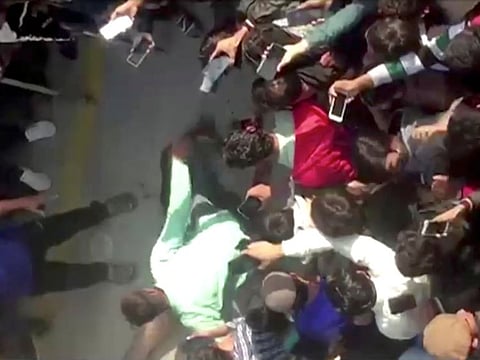People gather around the body of a Sri Lankan manager after an attack on a factory in Sialkot on December 3, 2021, in this screen grab taken from a video. 