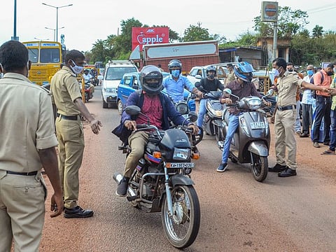 Police personnel direct commuters to undergo RT-PCR COVID-19 testing at Talapady checkpost of the Karnataka-Kerala state border, in Mangaluru.