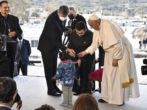 Pope Francis (R) meets a child refugee at the Reception and Identification Centre (RIC) in Mytilene on the island of Lesbos on December 5, 2021.