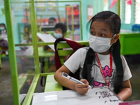 Students seated on chairs with plastic barriers attend a class as several schools in the Philippines' capital reopen for the first time since the coronavirus disease (COVID-19) pandemic, in Pasay City, Metro Manila, Philippines, December 6, 2021.