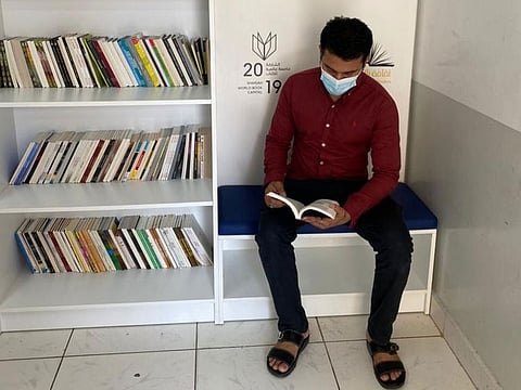 A worker selects a book from a new library installed at an employees' accommodation in Sharjah under the ongoing initiative