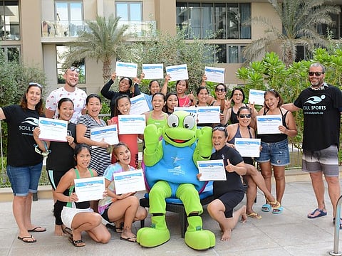 Participants in a swimming safety awareness programme pose with their certificates.