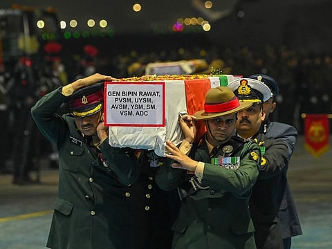 Army officers carry the coffins containing the mortal remains of India's defence chief General Bipin Rawat and 12 other victims who lost their lives in a helicopter crash a day earlier, during a tribute ceremony at Palam Air Force station in New Delhi on December 9, 2021. AFP
