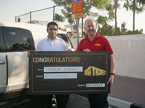 Harun Sheikh receiving his Dh1m cheque in the parking lot from the Big Ticket host Richard.