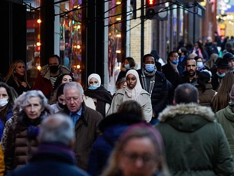 Shoppers walk along Oxford Street in central London on December 10, 2021. The UK government will from Monday tighten virus restrictions in England as Omicron variant cases surge, including guidance to work from home and mandatory COVID passports.  