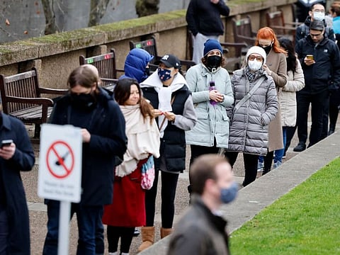 People queue up to receive a dose of a vaccine dose outside Guy's and St Thomas' Hospital in central London on December 13, 2021. 