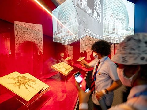 Students study the pages of famous date archives on display at the France Pavilion