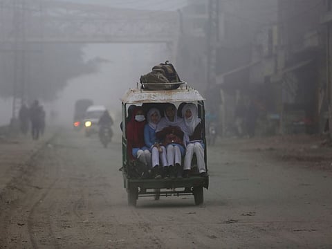 Students travel on a rickshaw to go their school as heavy fog reduces visibility, in Lahore, on Friday, December 17, 2021. 