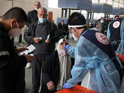 A Palestinian woman is tested for COVID-19 by an Israeli medic before entering in to Israel by the Erez border crossing from the Gaza strip on December 20, 2021.  