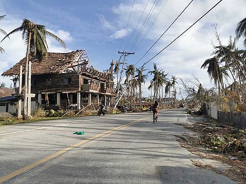 A cyclist travels past destroyed vegetation and houses along a road in General Luna, Siargao island on December 21, 2021, days after super Typhoon Rai devastated the island. 