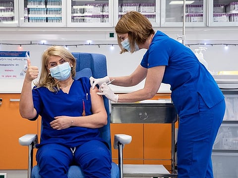 Efstathia Kambissiouli, left, a Greek nurse working in a state hospital intensive care, receives an injection with a dose of COVID-19 vaccine, in Athens, Sunday, December 27, 2020. 