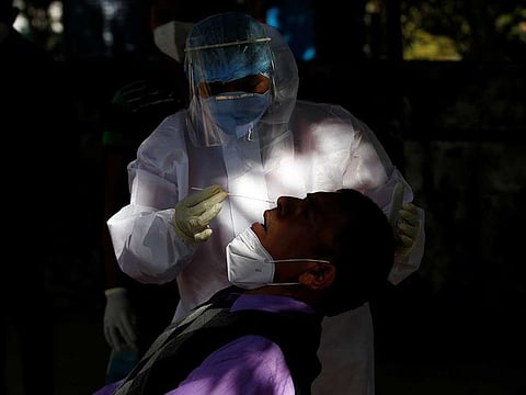 A healthcare worker wearing personal protective equipment (PPE) collects a swab sample from a person during a rapid antigen testing campaign for the coronavirus disease (COVID-19), in Gandhinagar, India
