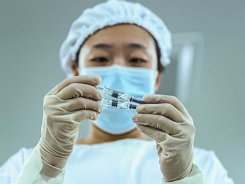 A staff member inspects syringes of COVID-19 inactivated vaccine products at a packaging plant of the Beijing Biological Products Institute Co., Ltd, a unit of state-owned Sinopharm in Beijing. 
