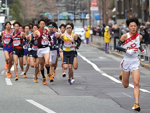 Chuo University runner Yamato Yoshii (R) runs ahead of the group during the opening day of the two-day Tokyo-Hakone collegiate Ekiden long-distance road relay run in Tokyo on January 2, 2022.