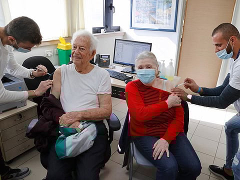 Zvi 93 (left) and Yossefta 84, an Israeli couple, receive their fourth dose of the Pfizer-BioNTech COVID-19 vaccine at a clinic of Clalit Healthcare Services in Israel's Mediterranean coastal city of Tel Aviv on January 3, 2022. 