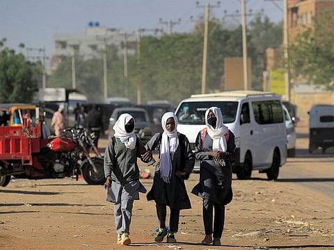 School girls walk along the side of a road in the Jarif West district of Sudan's capital Khartoum on January 3, 2022.