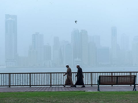 Residents take a walk on a cold foggy morning at Buheirah corniche in Sharjah. 