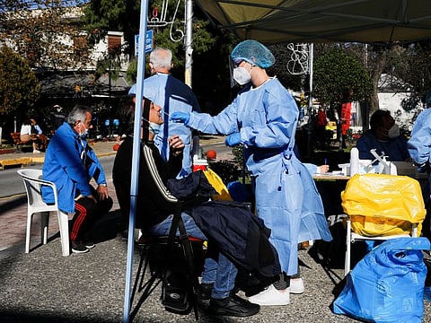 A healthcare worker takes a swab sample from a man for a rapid antigen test in Athens, Greece, on January 3, 2022. 